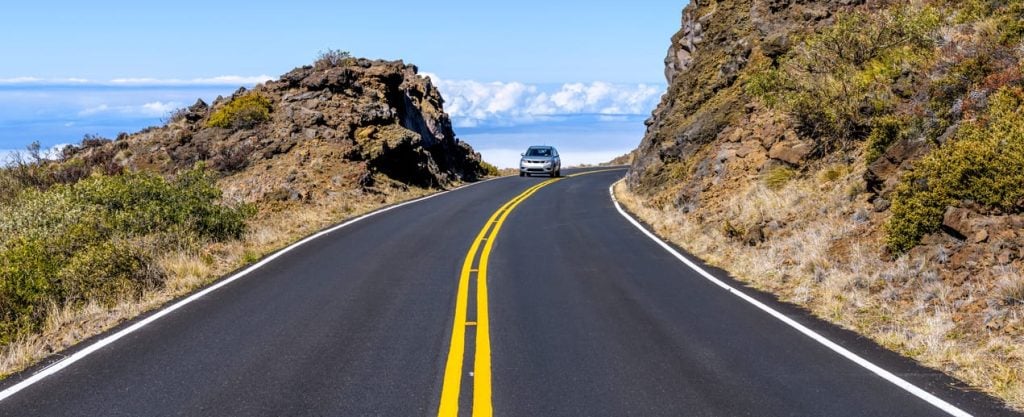 Winding Road - A mid-size SUV driving on a curvy and high elevation section of Haleakala Highway in Haleakala National Park on a bright sunny afternoon. Maui, Hawaii, USA.