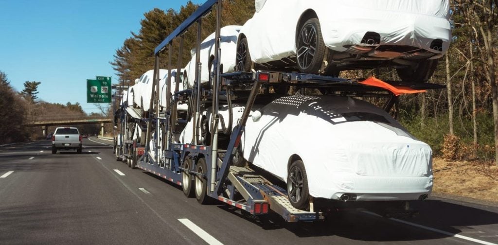 New cars being delivered by a car transporter truck on the freeway