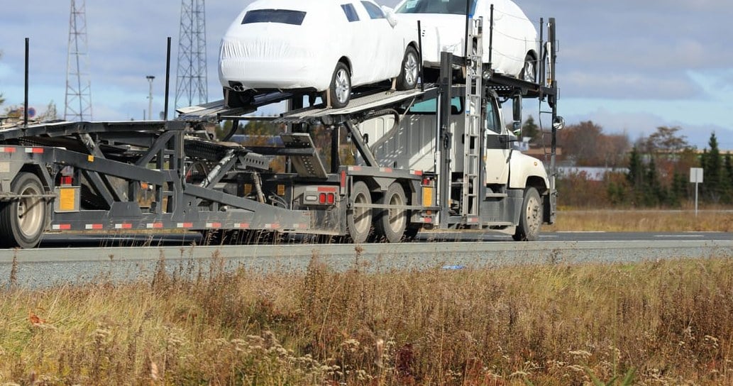 A car carrier hauling covered vehicles on a highway