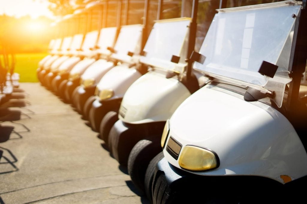 Golf carts line up in the golf course in the morning.