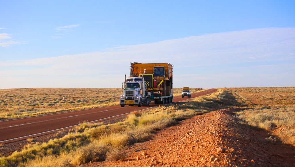 Truck oversize rides on road. Large truck driven mining dumper.