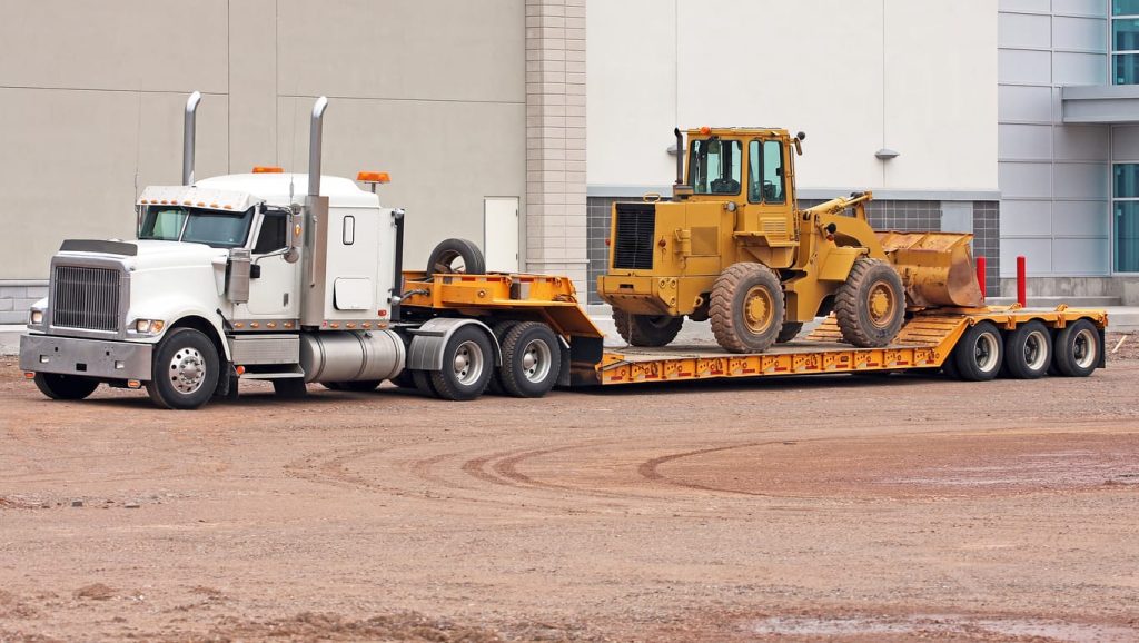 Conventional tractor hauling a wheel loader on a lowboy trailer