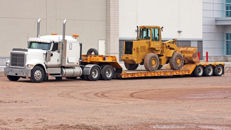 Conventional tractor hauling a wheel loader on a lowboy trailer