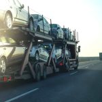 Car transporter trailer loaded with many cars on a highway, motion blur effect.