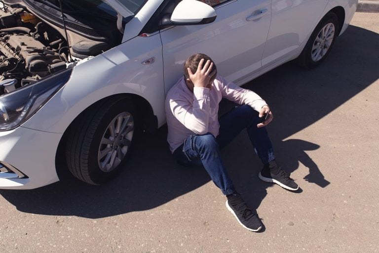 A man sitting near a faulty car. Auto repair shop