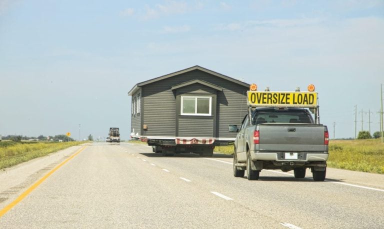 Escort truck with an oversize load sign leading a wide modular building move