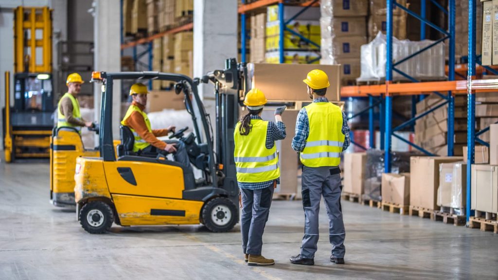 Warehouse crew with forklifts including a stand up unit