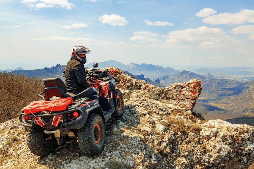 Man in helmet sitting on ATV quad bike in mountains