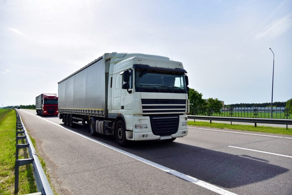 Truck with Semi-trailer driving along highway. Goods Delivery by roads. Services and Transport logistics. Object in motion, soft focus.