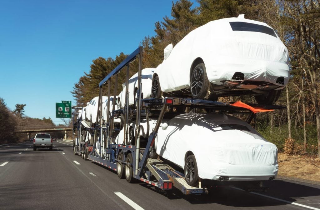 New cars being delivered by a car transporter truck on the freeway