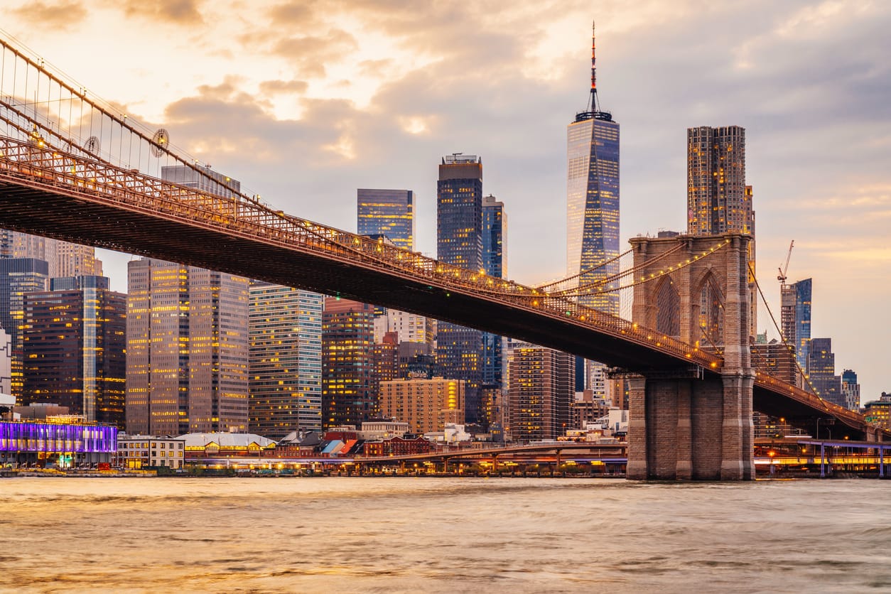 New York City skyline at sunset with Brooklyn Bridge and Lower Manhattan