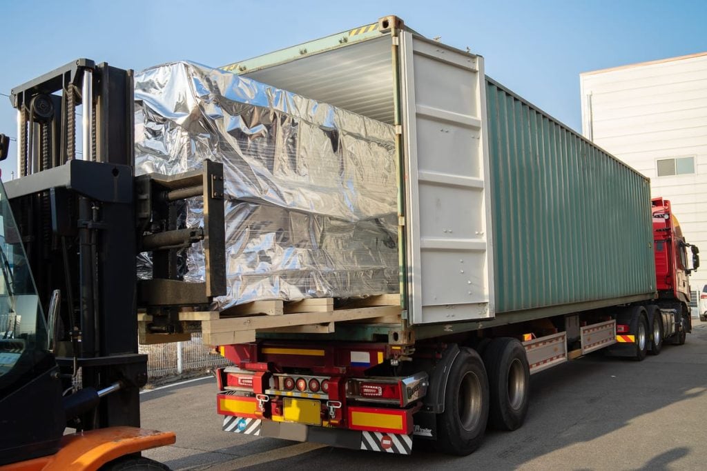 loading machinery into a container on a big trailer truck with a folk lift