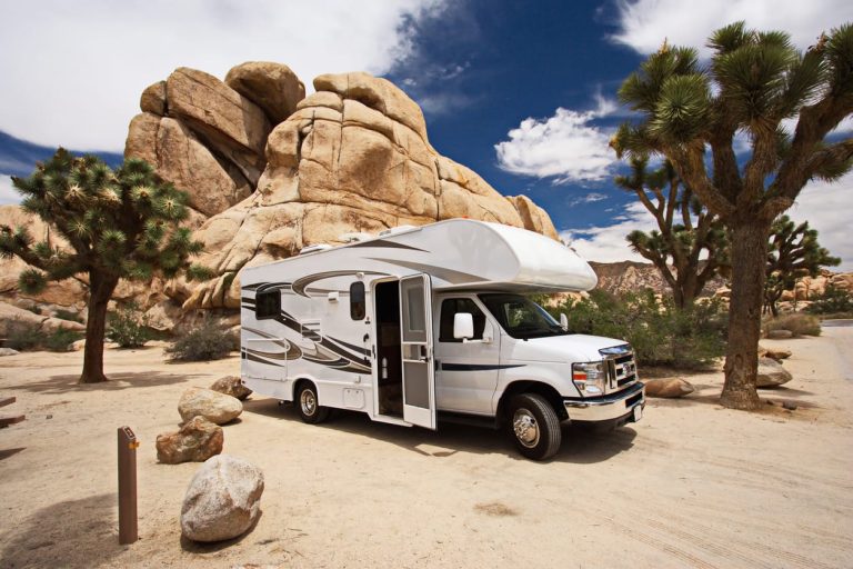 Class C motorhome parked among desert rocks and trees