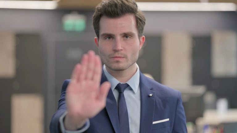 Person in a suit holding up a hand in a stop gesture