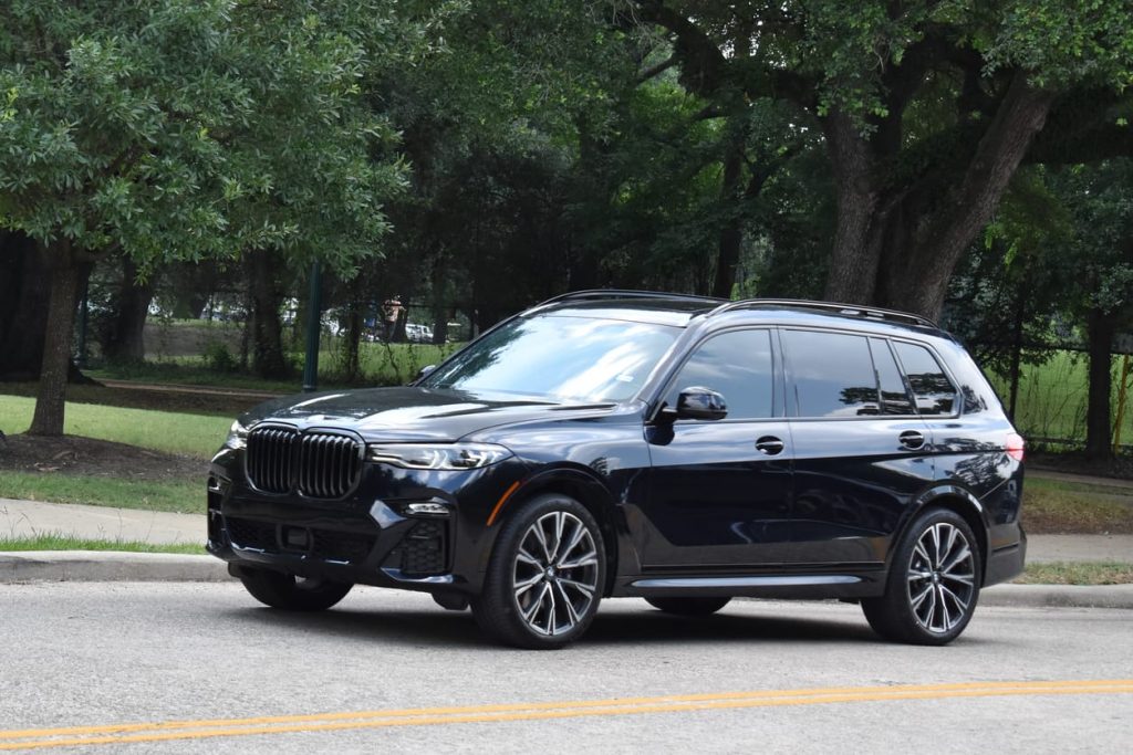 Black BMW X5 parked on grass beside trees