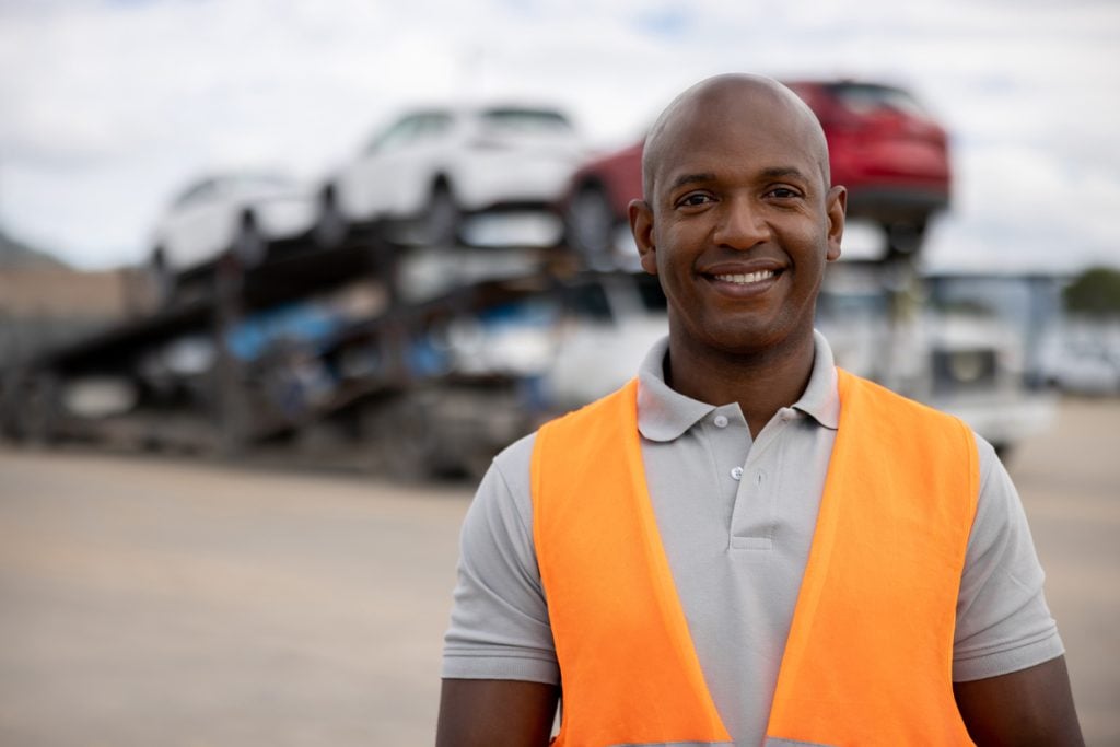 Man working at a distribution warehouse and loading vehicles on a car transporter