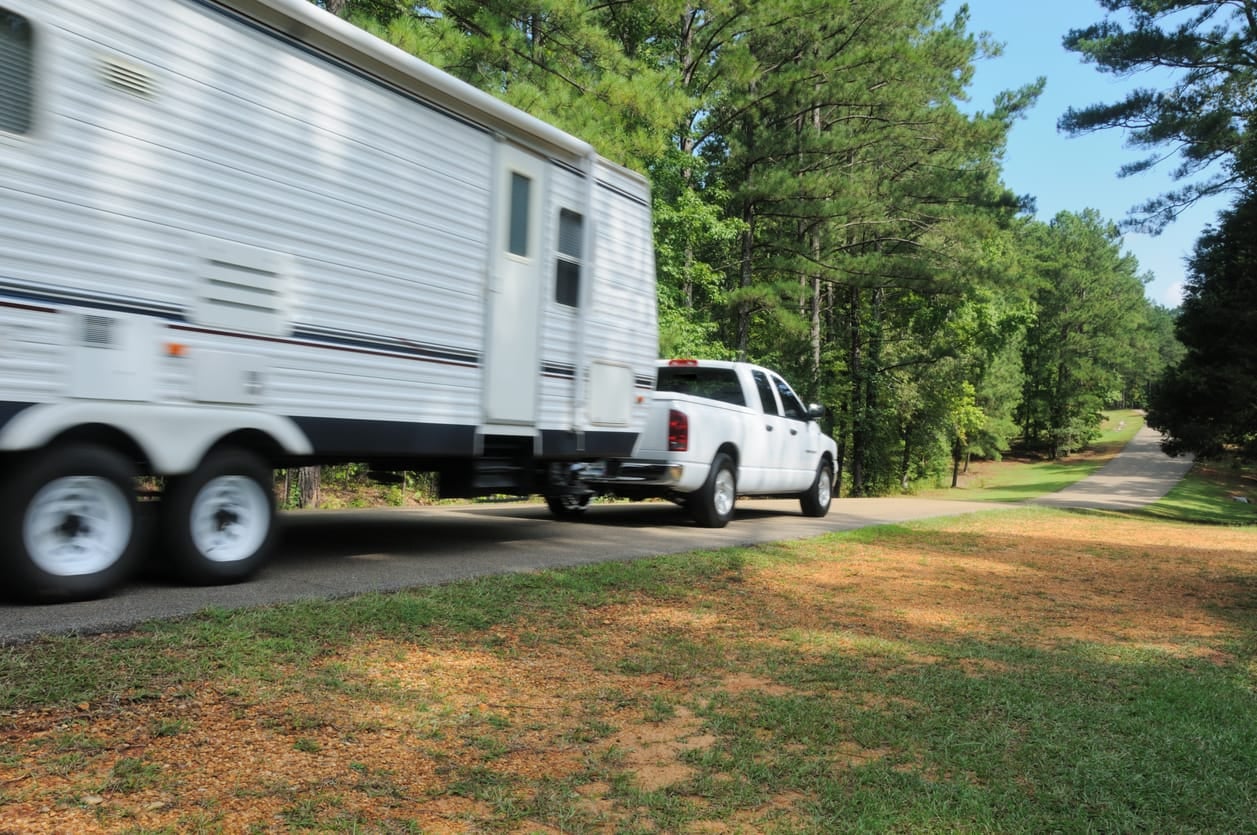 Pickup truck towing a travel trailer on a country road