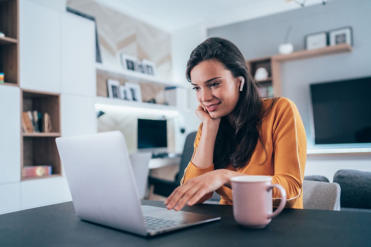 Young and beautiful woman using her laptop and Wireless earbuds at home