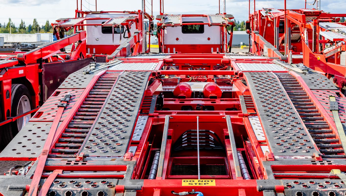 Row of car hauling trucks waiting at an industrial lot
