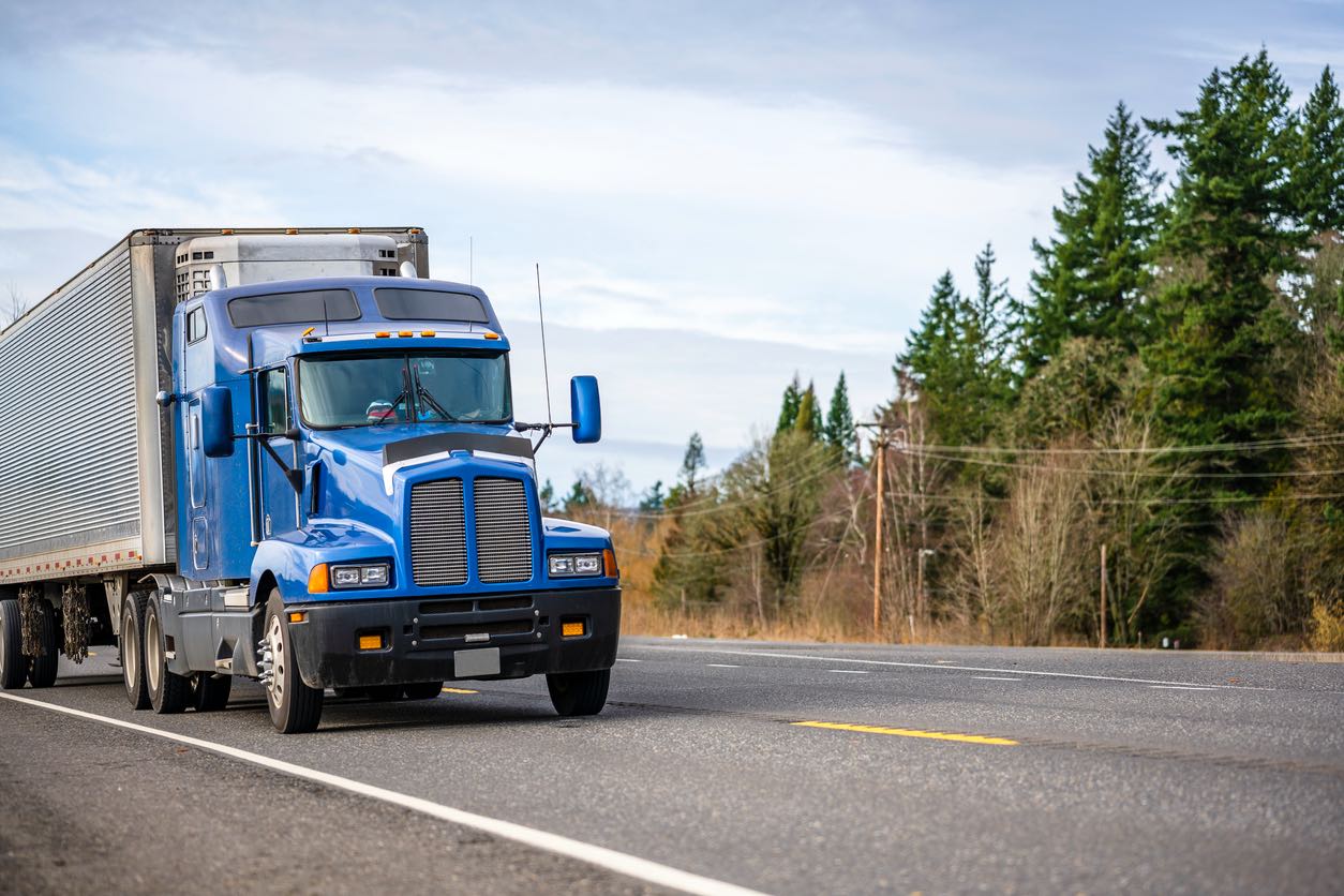 Conventional tractor with a trailer on a tree lined highway