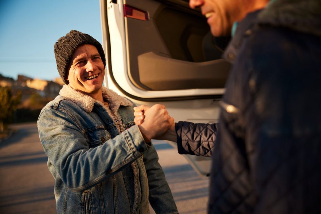 Two drivers shaking hands beside a truck