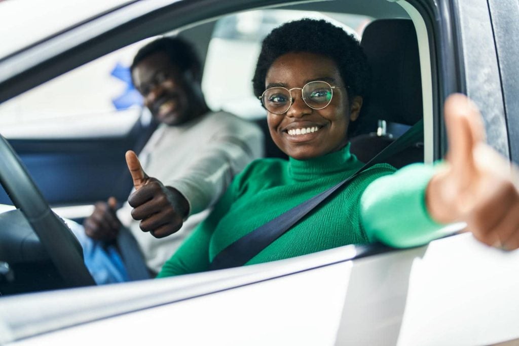 Couple in a car giving a thumbs up before a trip