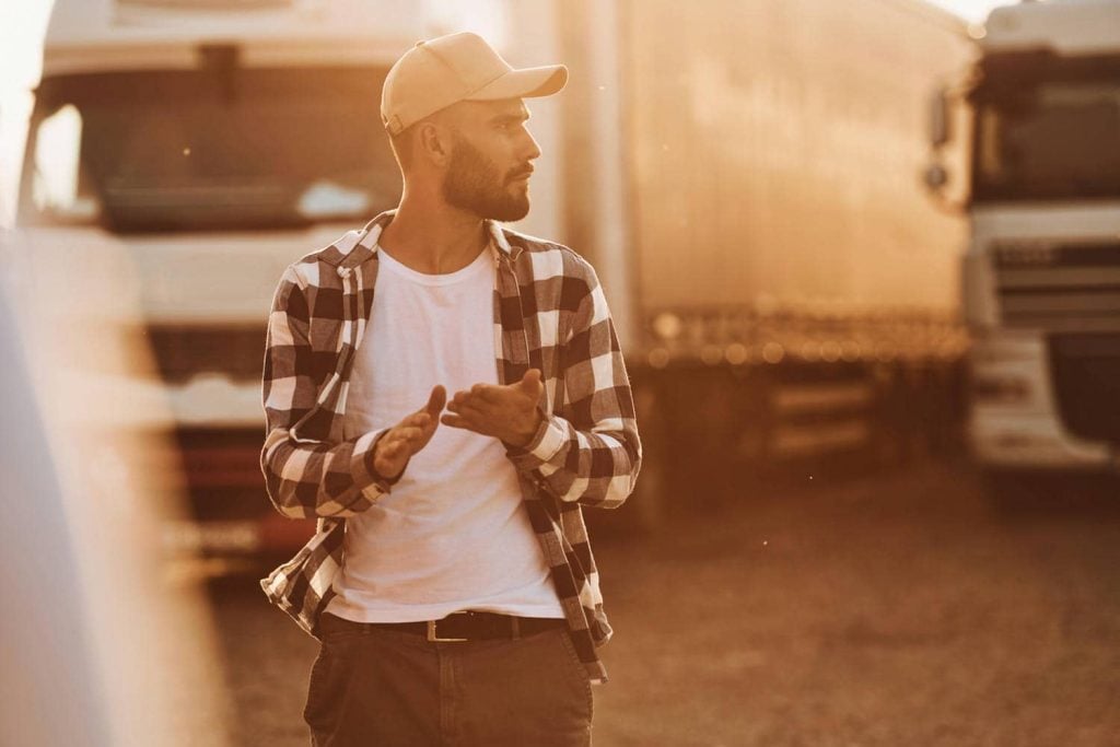 Driver walking beside parked trucks in sunlight