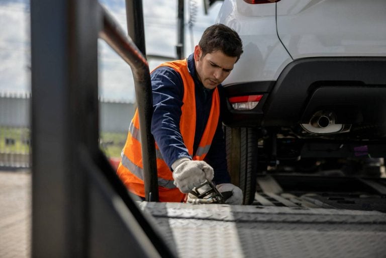 Operator securing a vehicle on a car transporter