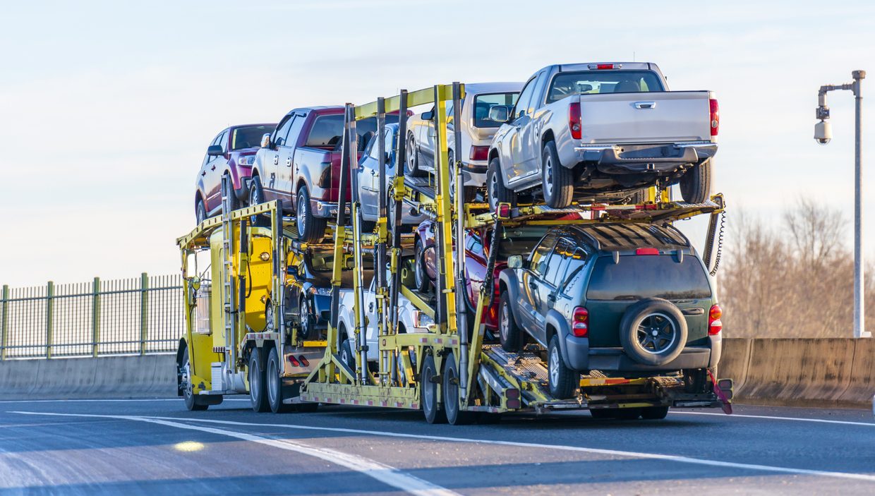 Big-rig-yellow-car-hauler-semi-truck-transporting-cars-on-two-levels-semi-trailer-driving-on-the-overpass-road-