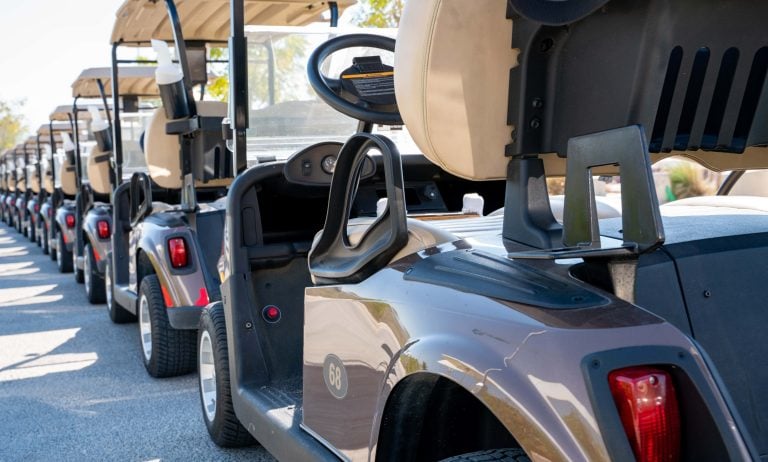 Background image of multiple golf carts parked in order.