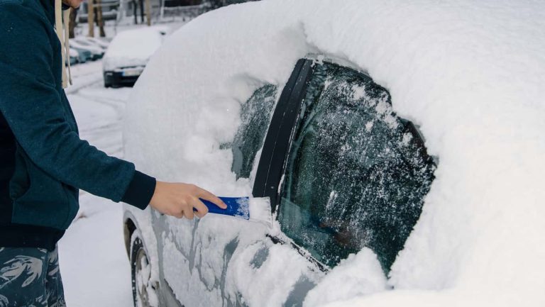 Removing ice and snow from the car glass with ice scraper