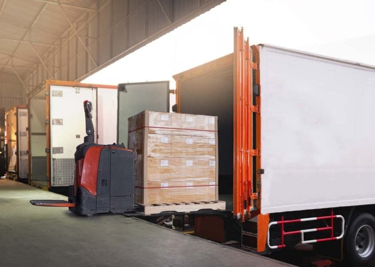 Electric Forklift Loading Shipment Boxes into Cargo Container. Cargo Trailer Truck Parked Loading at Dock Warehouse. Delivery Service. Shipping Warehouse Logistics. Freight Truck Transportation.