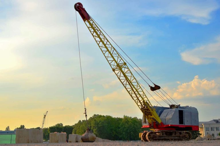 Large crawler crane or dragline excavator with a heavy metal wrecking ball on a steel cable