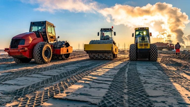 roller compacts soil in embankment on the highway construction. sand consolidation on road. Compactor driving on sandy. wheel marks on the sand