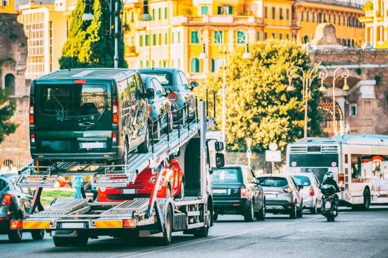 Auto-transport Carrying New Fiat Cars In European City Street. Auto Transport Broker Or Car Transporter. Auto-transport Carrying New Fiat Cars In City Street. Auto Transport Broker Or Car Transporter.