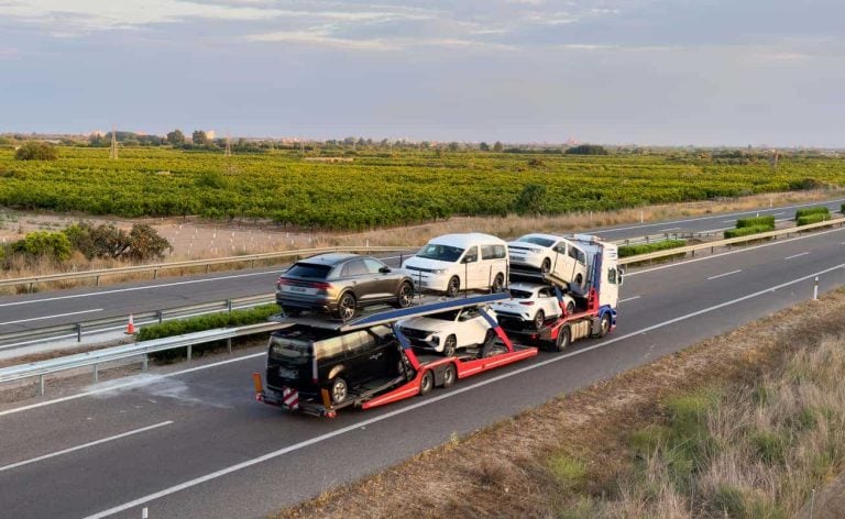 Car carrier trailer transports cars on highway. Auto transport and car shipping services concept.