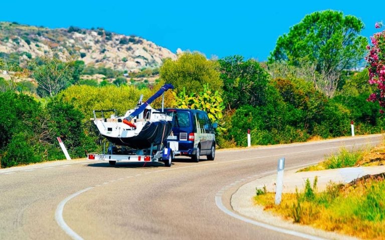 Car with yacht or motor boat in road in Sardinia reflex