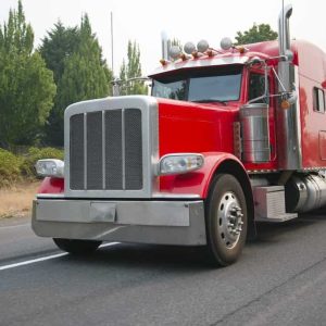 Powerful red big rig semi truck with flat bed step down semi trailer move on road for loading cargo