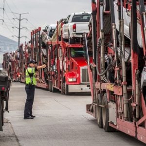 A line of loaded car carrier trucks waiting at a loading area