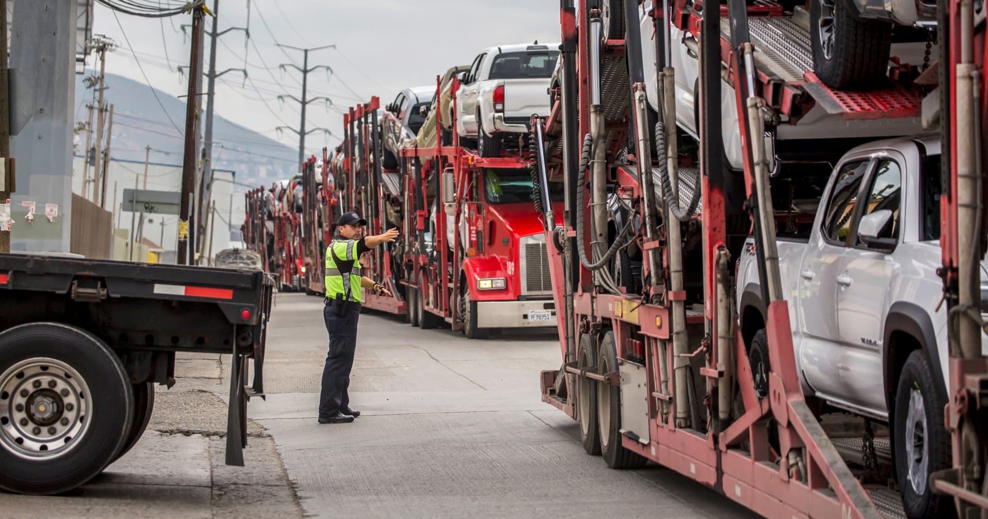 A line of loaded car carrier trucks waiting at a loading area