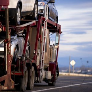 Classic car hauler semi trailer loaded with cars on the road at dusk
