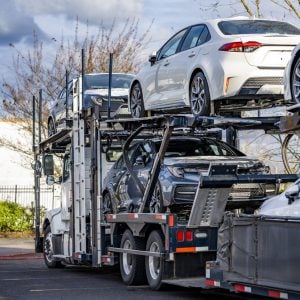 Two-level car hauler trailer loaded with new sedans on a parking lot