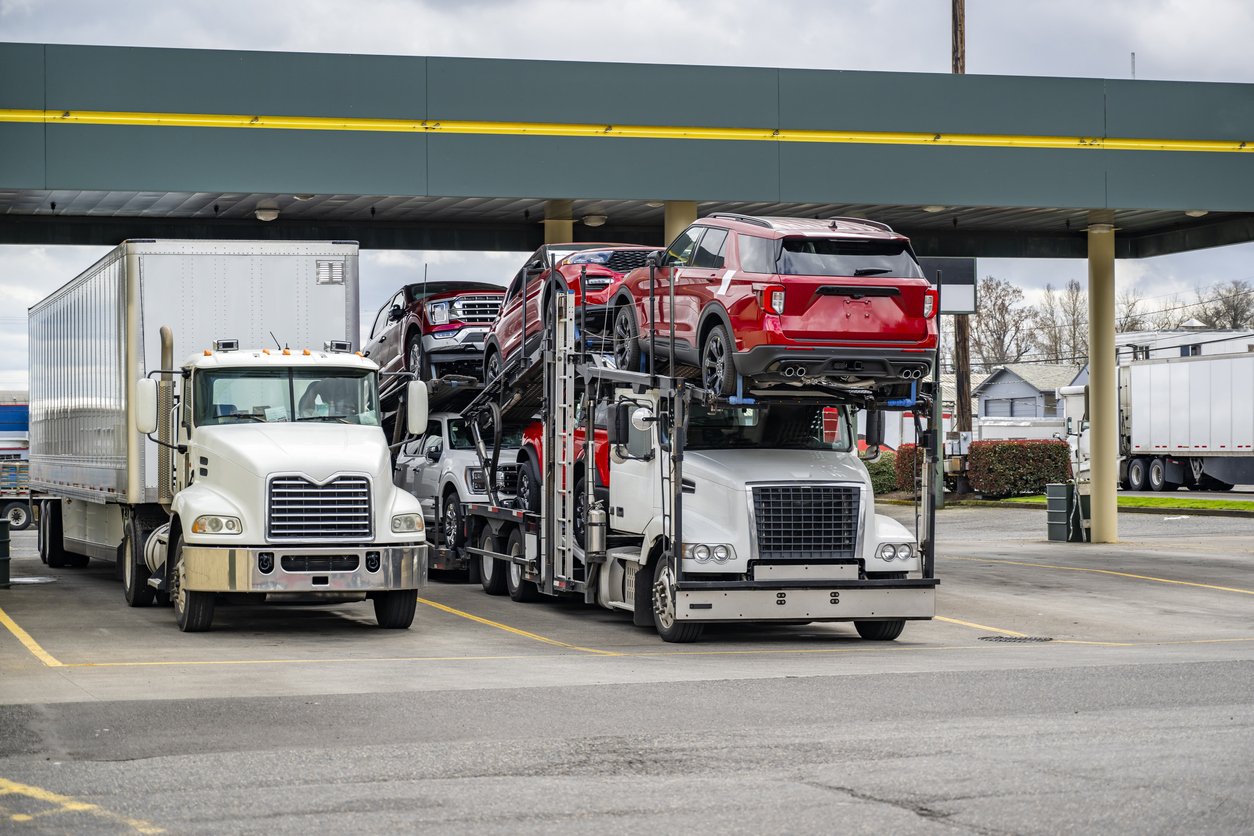 Car hauler semi truck loaded with red SUVs parked at a truck stop