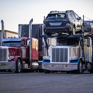 Car carrier semi truck loaded with SUVs parked among other trucks at twilight