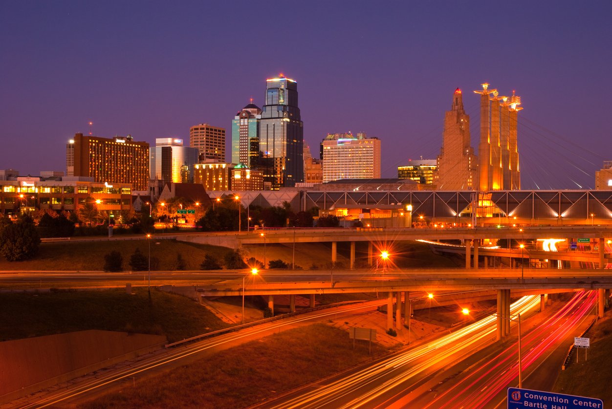 Kansas City downtown skyline and freeway interchange lit up at dusk