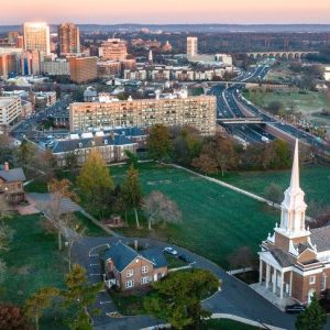 Aerial view of New Brunswick, New Jersey with a church steeple and the downtown skyline at sunset