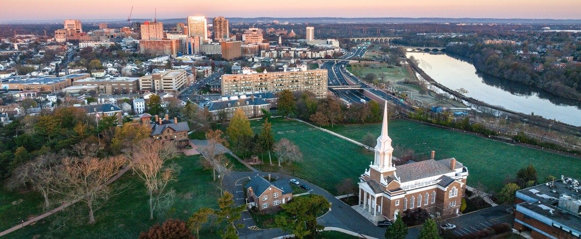 Aerial view of New Brunswick, New Jersey with a church steeple and the downtown skyline at sunset
