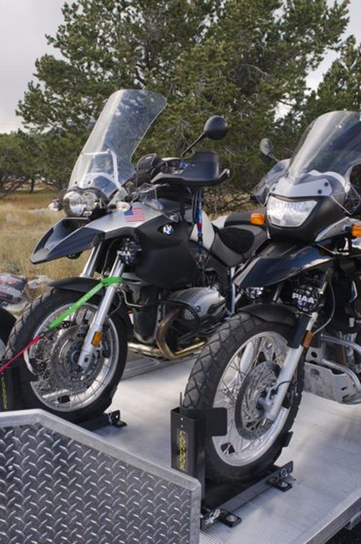 Two motorcycles secured in wheel chocks on a transport trailer