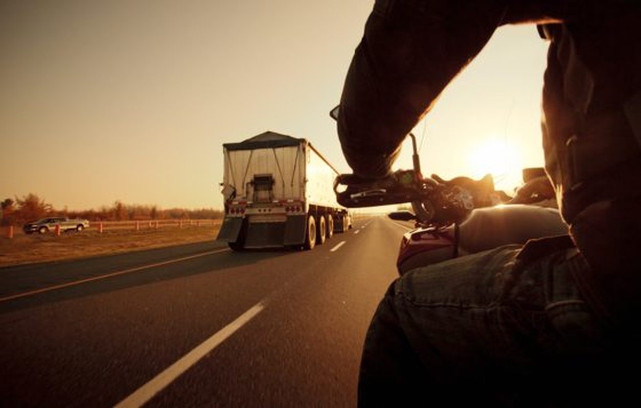 Rider view of a motorcycle passing a truck at sunset
