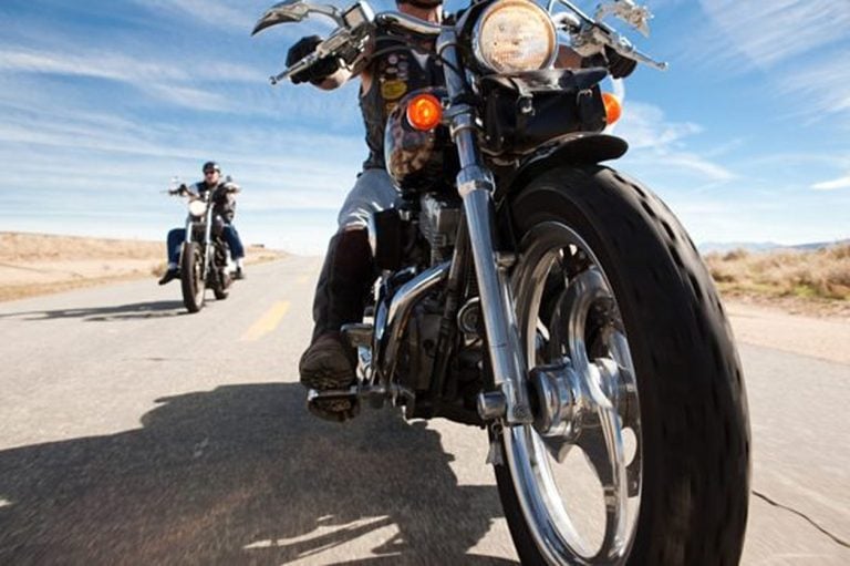 Two riders on cruiser motorcycles on an open desert road